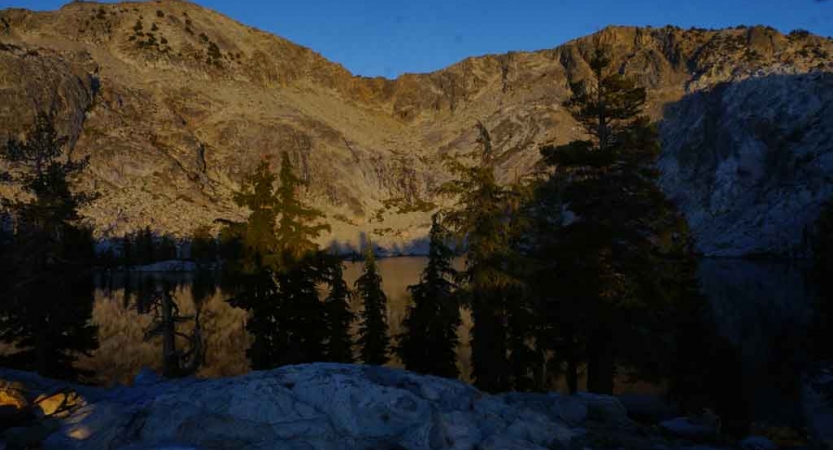 a body of water lies among trees and hills in yosemite